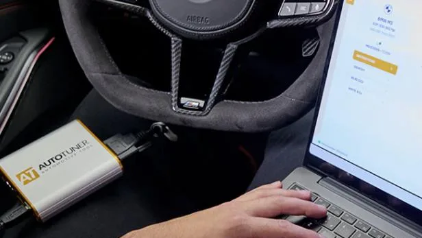 AutoTuner programming equipment connected to a vehicle beside a workshop laptop